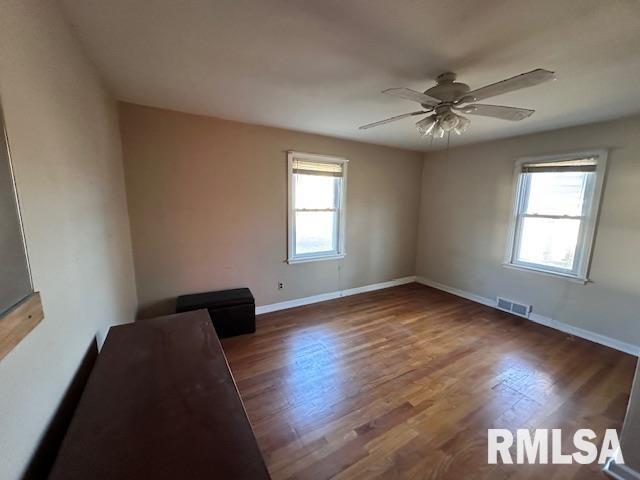 empty room with dark hardwood / wood-style flooring, ceiling fan, and plenty of natural light