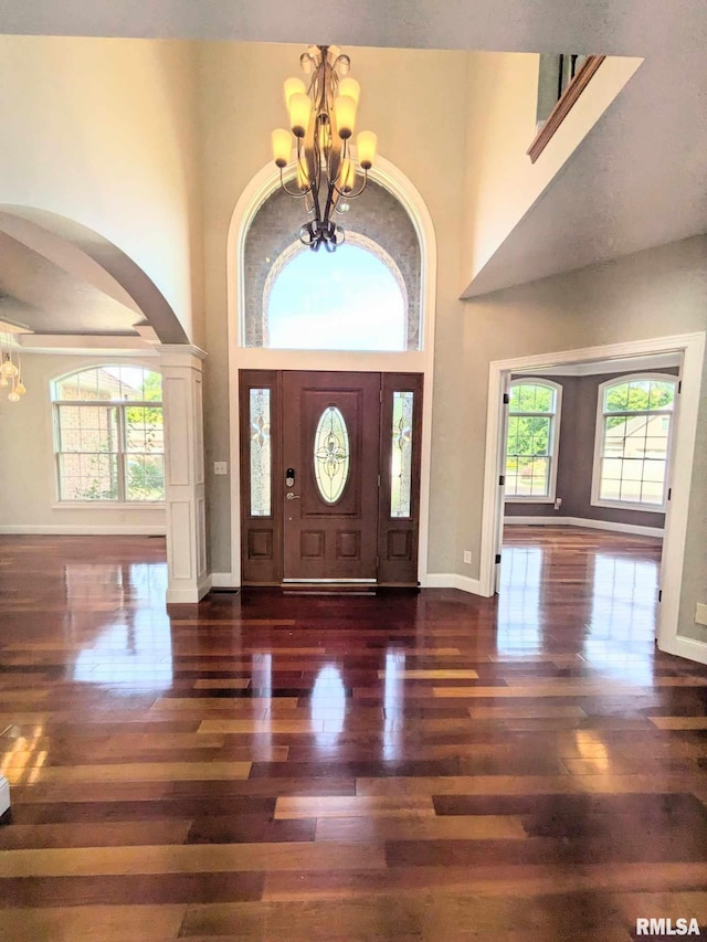 entrance foyer with a chandelier, a high ceiling, and dark wood-type flooring