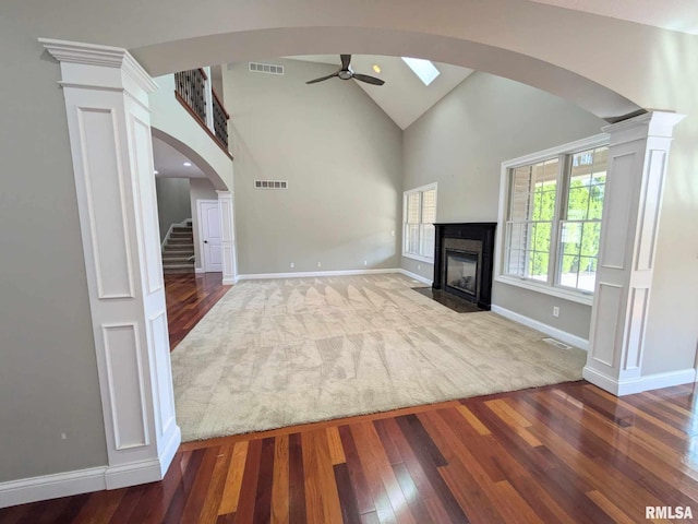 unfurnished living room featuring a fireplace, hardwood / wood-style floors, decorative columns, and ceiling fan