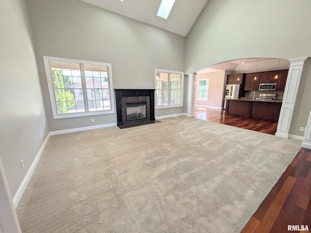 unfurnished living room featuring ornate columns, high vaulted ceiling, and dark hardwood / wood-style floors