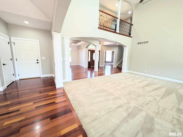 entryway with ornate columns, dark hardwood / wood-style flooring, and high vaulted ceiling