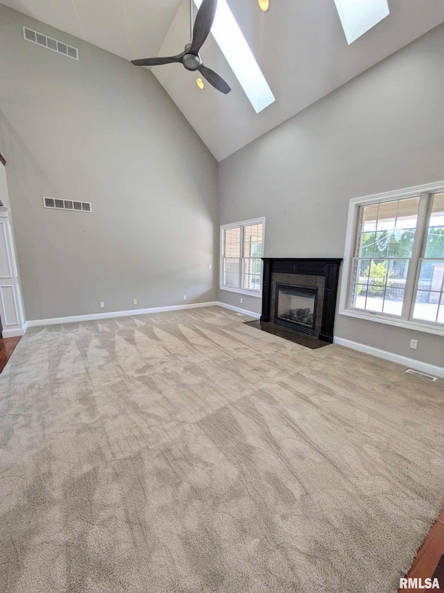 unfurnished living room featuring light carpet, high vaulted ceiling, ceiling fan, and a premium fireplace