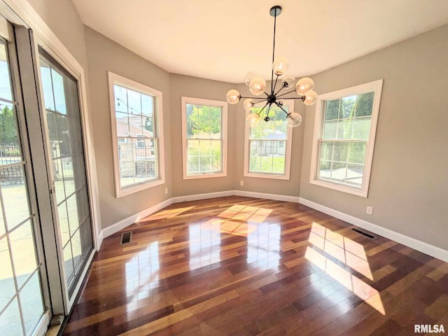 unfurnished dining area featuring a notable chandelier, a healthy amount of sunlight, and dark hardwood / wood-style floors