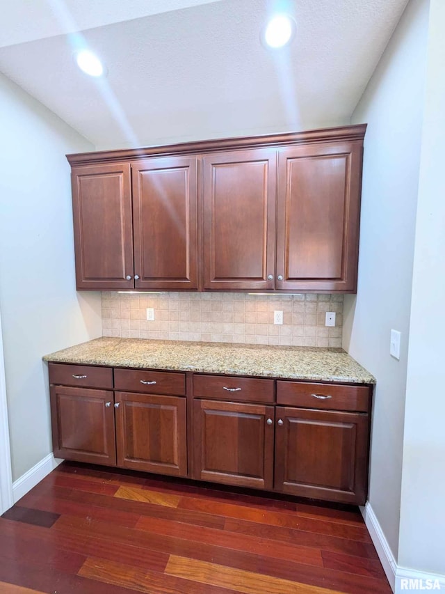 kitchen featuring backsplash, dark hardwood / wood-style floors, and light stone counters