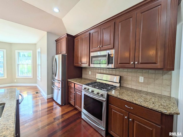 kitchen with light stone counters, dark hardwood / wood-style flooring, stainless steel appliances, and vaulted ceiling