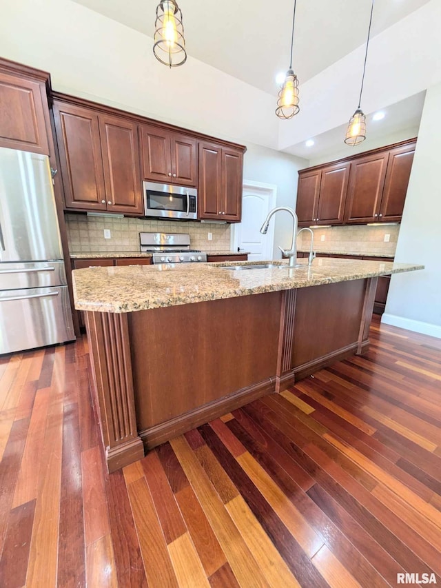 kitchen featuring sink, tasteful backsplash, dark hardwood / wood-style flooring, pendant lighting, and appliances with stainless steel finishes