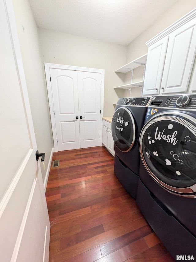 clothes washing area featuring cabinets, dark hardwood / wood-style flooring, and washing machine and clothes dryer