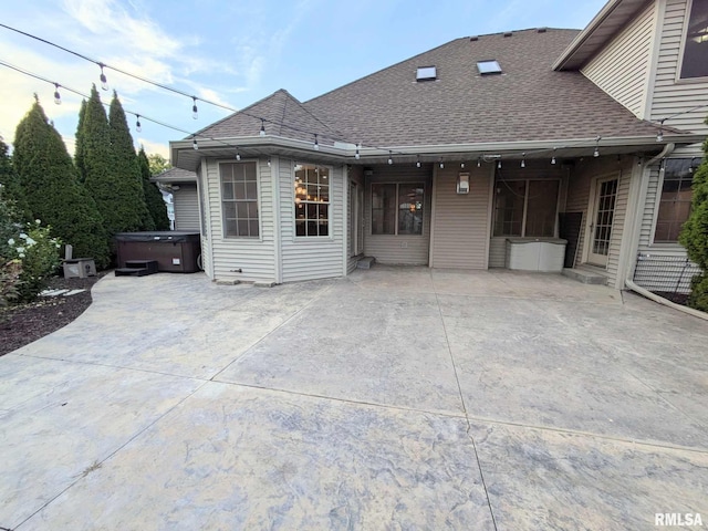 back of property featuring a patio and a hot tub