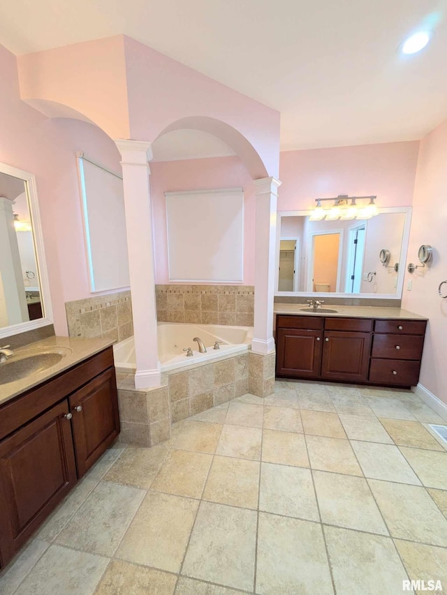 bathroom with vanity, ornate columns, and tiled bath