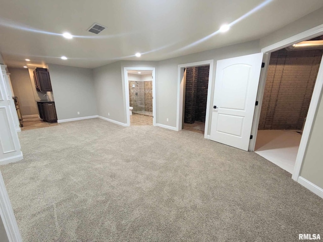 unfurnished bedroom featuring ensuite bath, a walk in closet, a closet, and light colored carpet