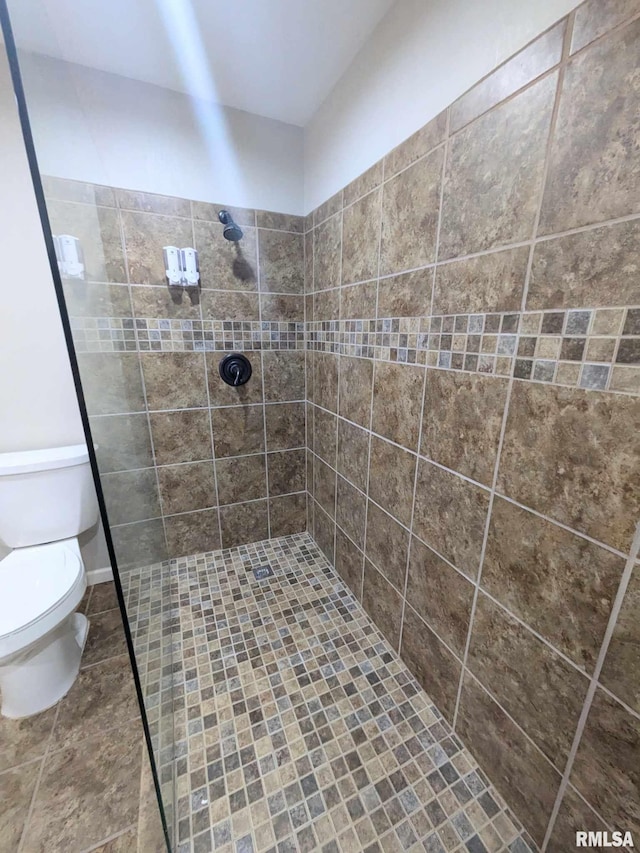 bathroom with a tile shower and toilet