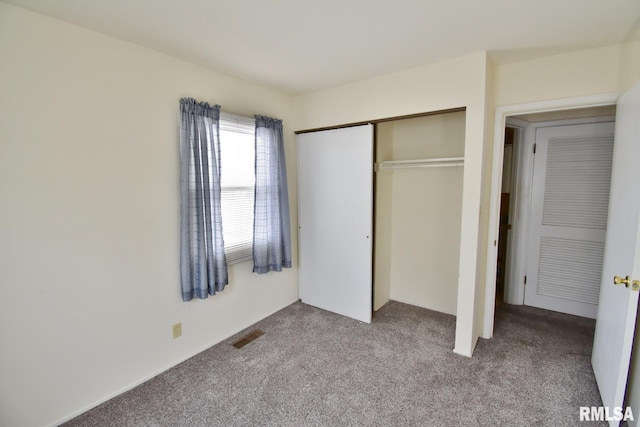 unfurnished bedroom with light colored carpet and a closet