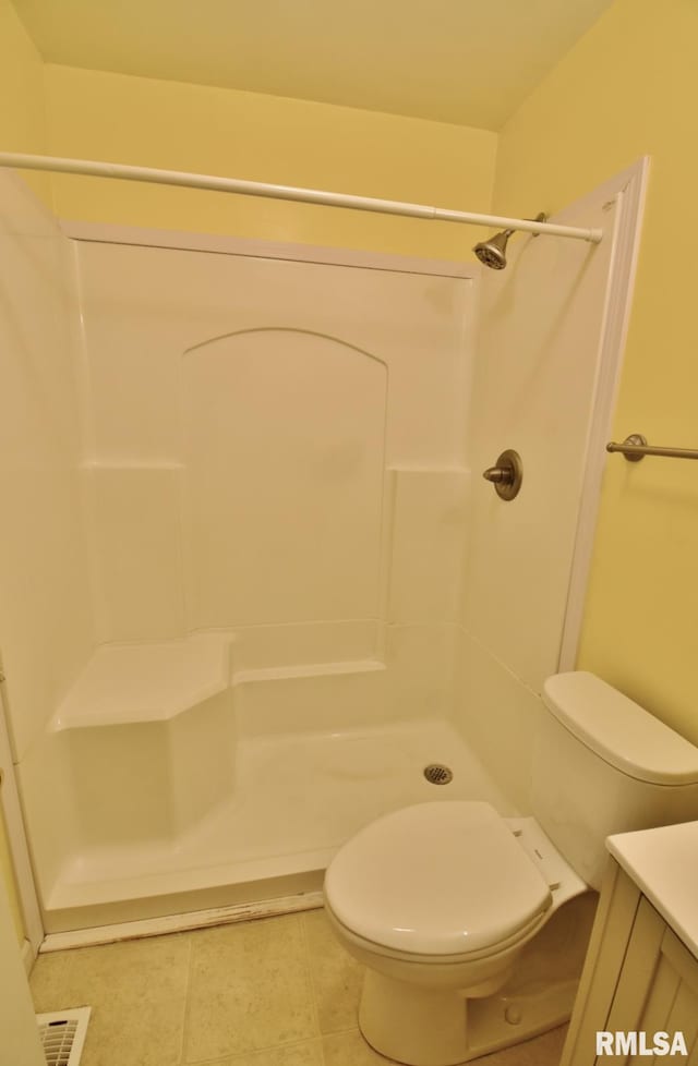 bathroom featuring tile patterned flooring, vanity, toilet, and walk in shower