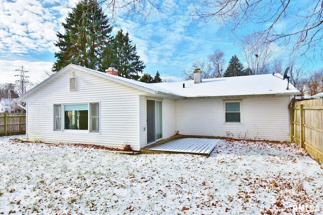 snow covered rear of property with a deck