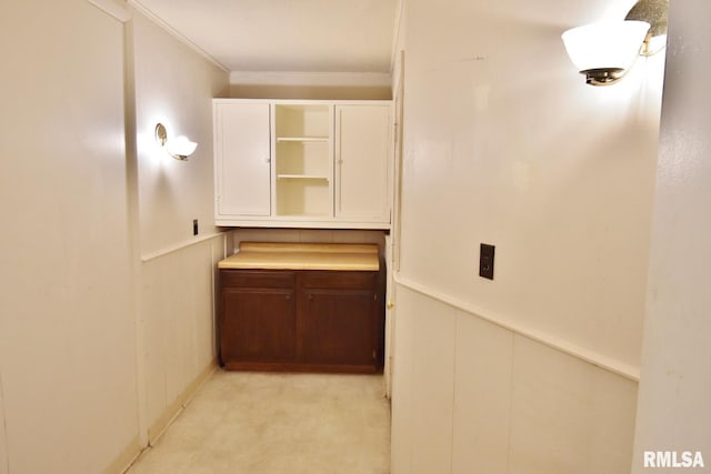 corridor featuring ornamental molding, light carpet, and wooden walls