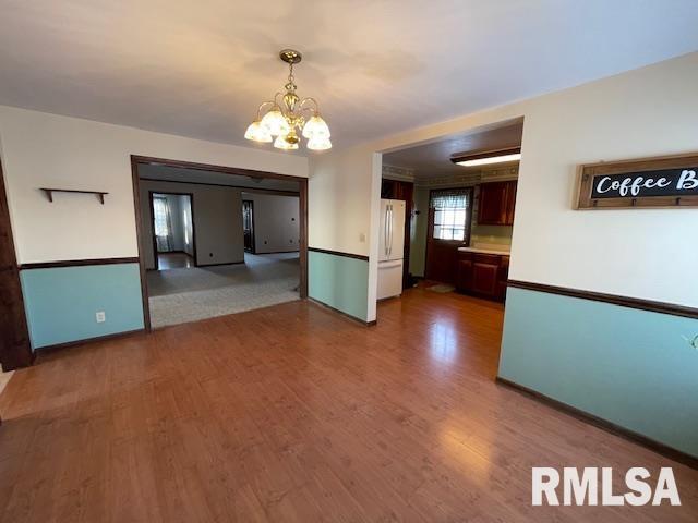 unfurnished room featuring hardwood / wood-style flooring and an inviting chandelier