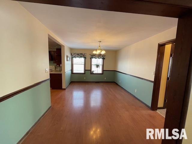 spare room featuring wood-type flooring and a notable chandelier