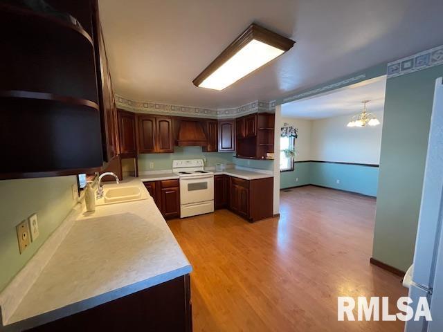 kitchen with sink, white electric stove, light hardwood / wood-style floors, pendant lighting, and custom exhaust hood