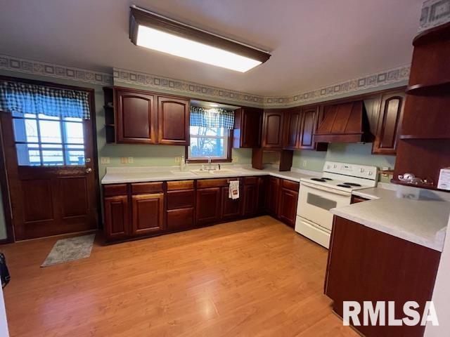 kitchen with premium range hood, white range with electric stovetop, sink, light wood-type flooring, and dark brown cabinets