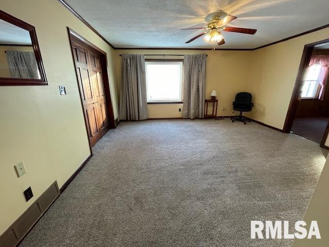 empty room featuring ceiling fan, crown molding, and carpet floors