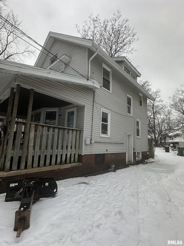 snow covered rear of property featuring a porch