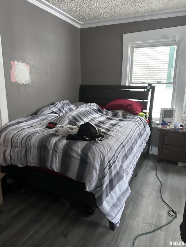 bedroom featuring ornamental molding, wood-type flooring, and a textured ceiling