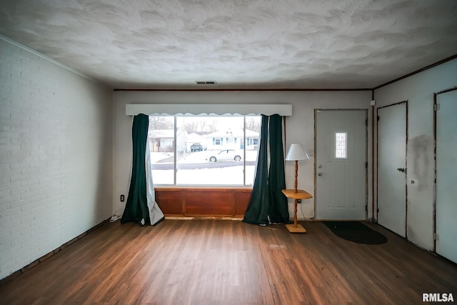 entrance foyer with dark hardwood / wood-style flooring and brick wall