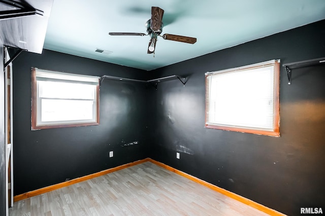 empty room with plenty of natural light, ceiling fan, and light wood-type flooring