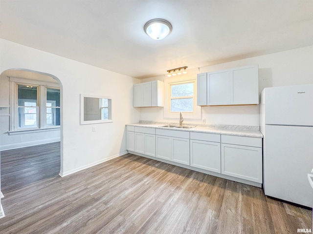 kitchen featuring white cabinetry, sink, light hardwood / wood-style flooring, and white refrigerator