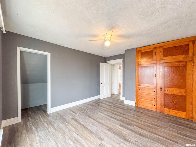 unfurnished bedroom with a textured ceiling, a closet, light hardwood / wood-style flooring, and ceiling fan