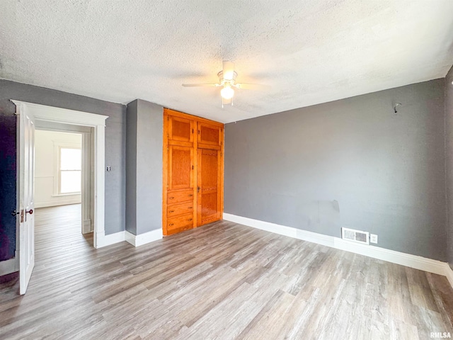 unfurnished bedroom with ceiling fan, a textured ceiling, and light wood-type flooring