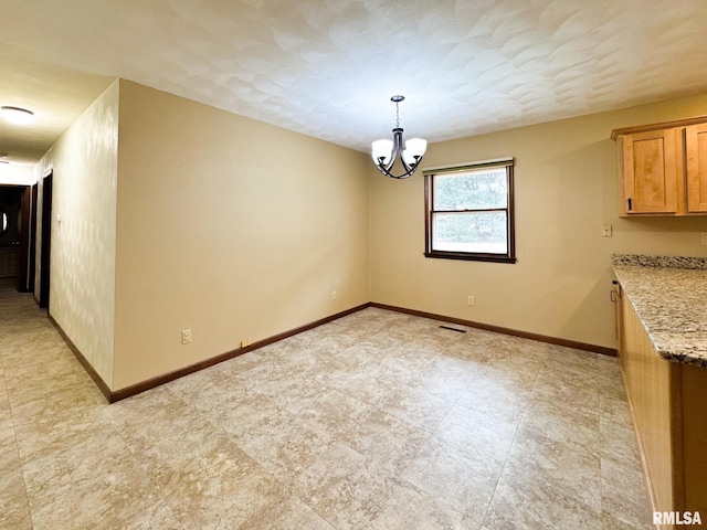 unfurnished dining area featuring a chandelier