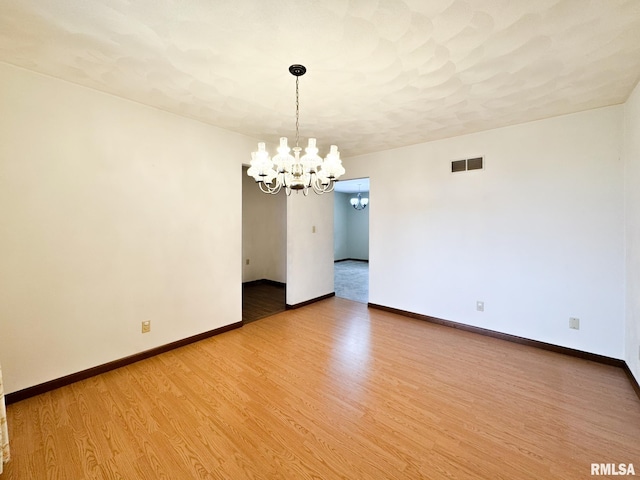 unfurnished room featuring a chandelier and wood-type flooring