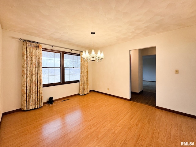 spare room with a notable chandelier, hardwood / wood-style flooring, and a textured ceiling