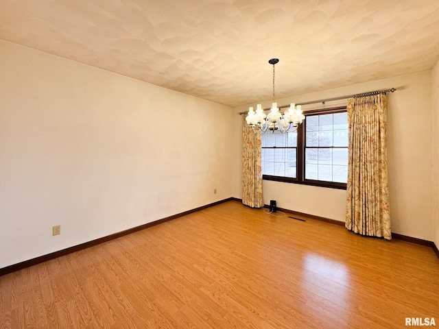 empty room featuring hardwood / wood-style floors and a chandelier