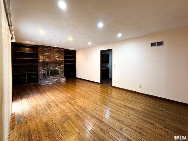 unfurnished living room featuring a brick fireplace and wood-type flooring