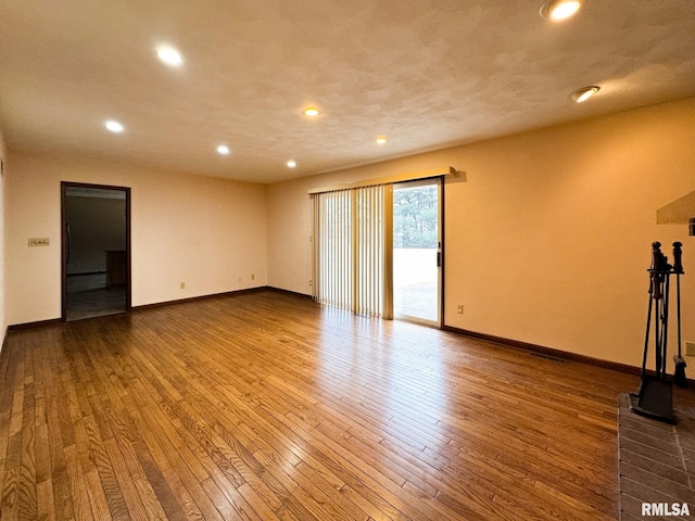 empty room with wood-type flooring, a baseboard radiator, and a textured ceiling