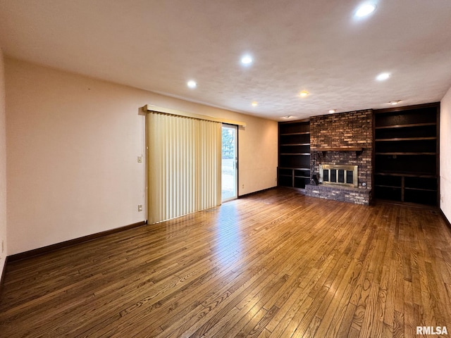 unfurnished living room featuring a fireplace, built in features, and wood-type flooring