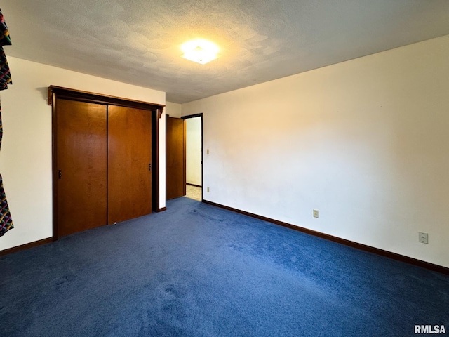 unfurnished bedroom with dark colored carpet, a textured ceiling, and a closet