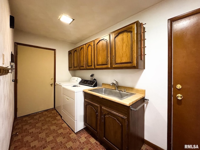 clothes washing area featuring sink, cabinets, and washer and clothes dryer