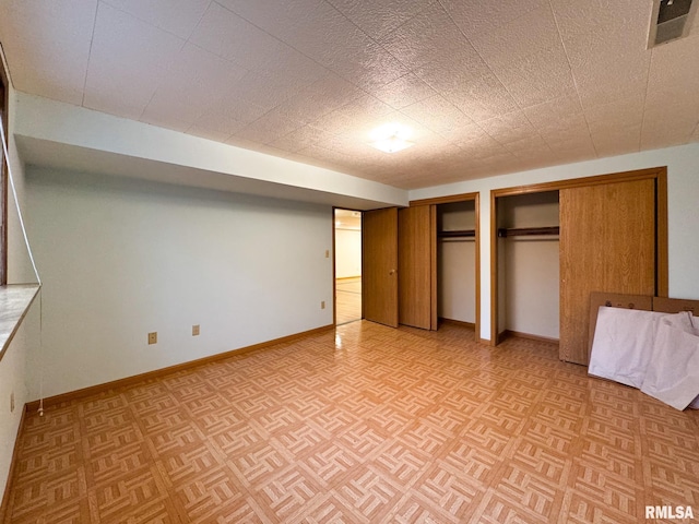 unfurnished bedroom featuring multiple closets and light parquet flooring