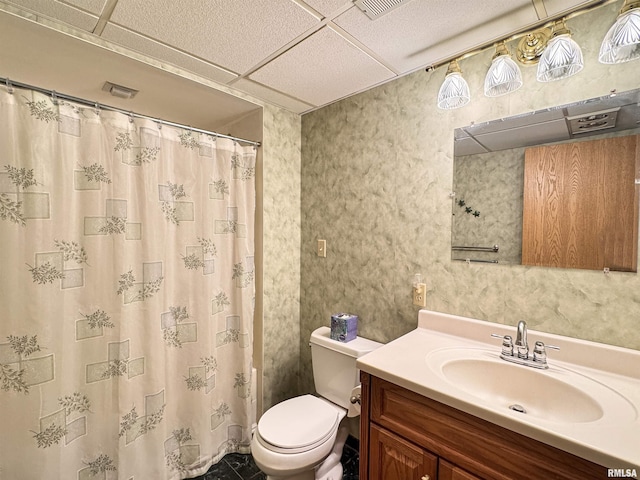 bathroom with vanity, toilet, and a drop ceiling