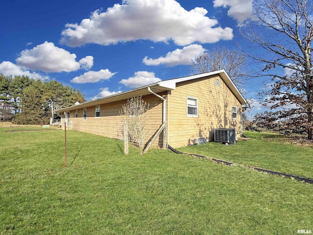 view of side of home featuring central AC unit and a yard