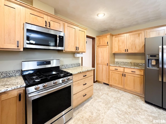 kitchen with light stone counters, appliances with stainless steel finishes, and light brown cabinets