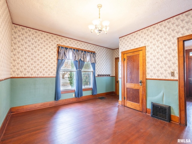 unfurnished room with a notable chandelier, dark hardwood / wood-style flooring, a textured ceiling, and crown molding