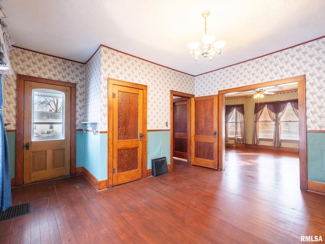 entrance foyer featuring a textured ceiling, crown molding, dark wood-type flooring, and ceiling fan with notable chandelier