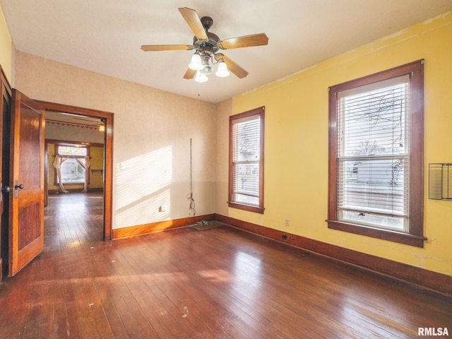 empty room featuring ceiling fan, dark hardwood / wood-style flooring, and a healthy amount of sunlight