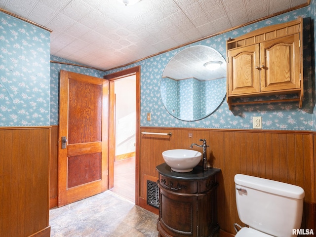 bathroom featuring wood walls, vanity, and toilet