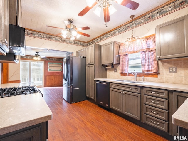 kitchen featuring appliances with stainless steel finishes, crown molding, sink, wood-type flooring, and decorative light fixtures