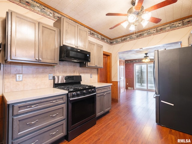 kitchen featuring dark hardwood / wood-style floors, backsplash, gray cabinets, appliances with stainless steel finishes, and ornamental molding